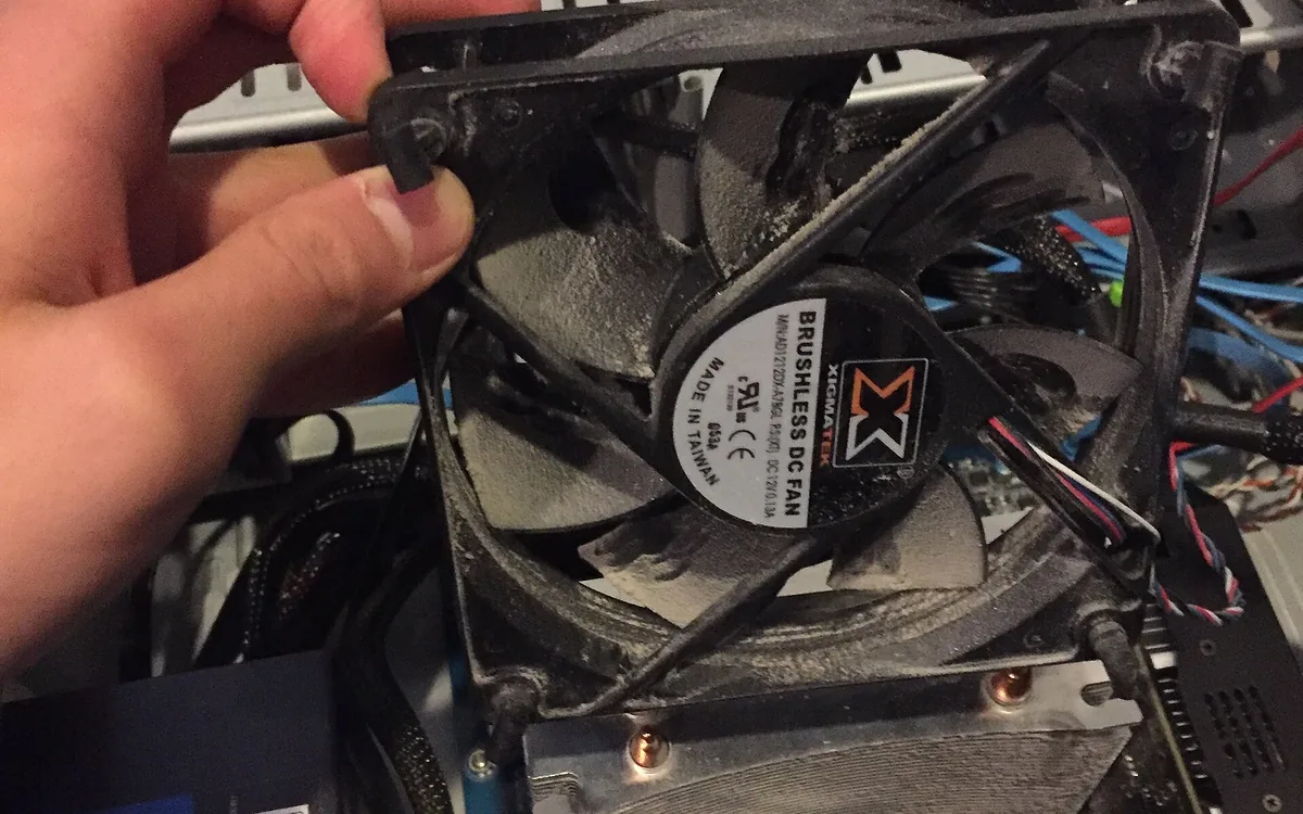 A dust-clogged CPU heatsink and fan being cleaned